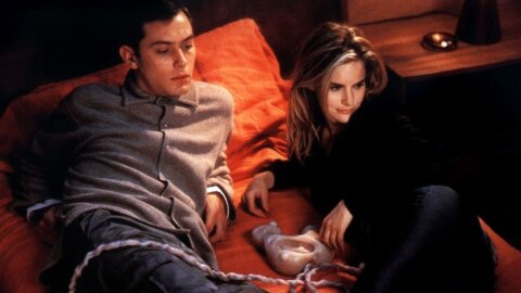 Sexy people on a bed but with yucky Cronenberg stuff, thus ruining it. eXistenZ movie backdrop.
